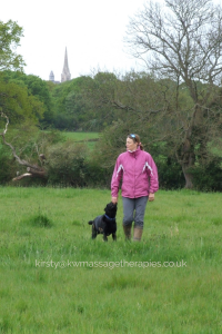 Kirsty walking her dog in a grassy field 